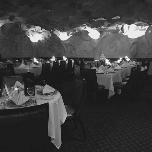 A black and white photo of a restaurant filled with tables and chairs