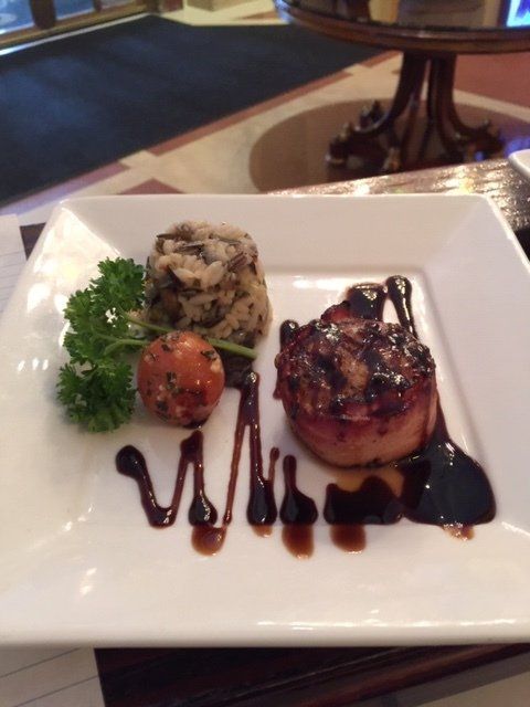 A white plate with a piece of meat and sauce on it