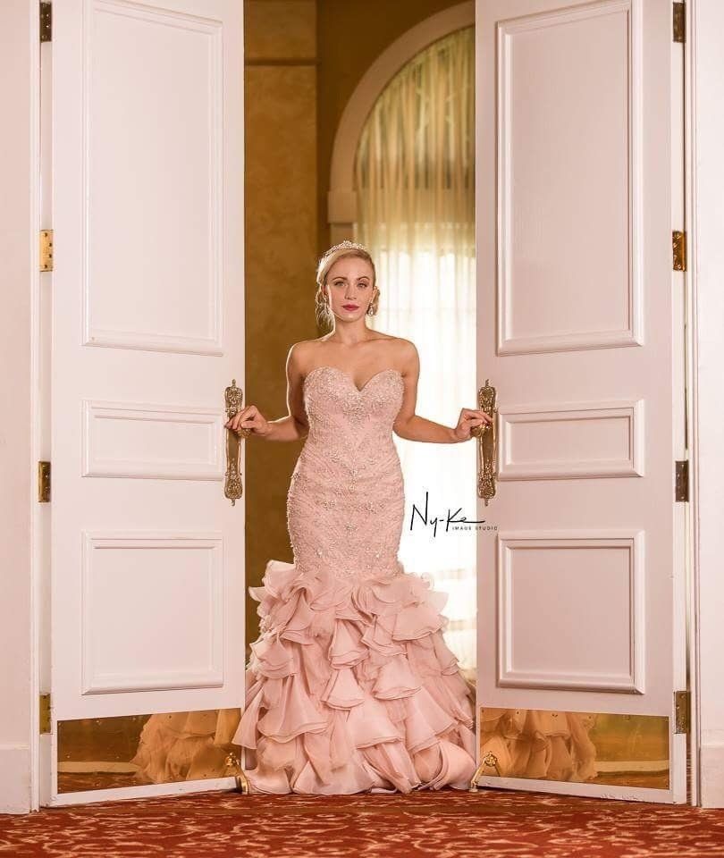A woman in a pink dress is standing in front of a door