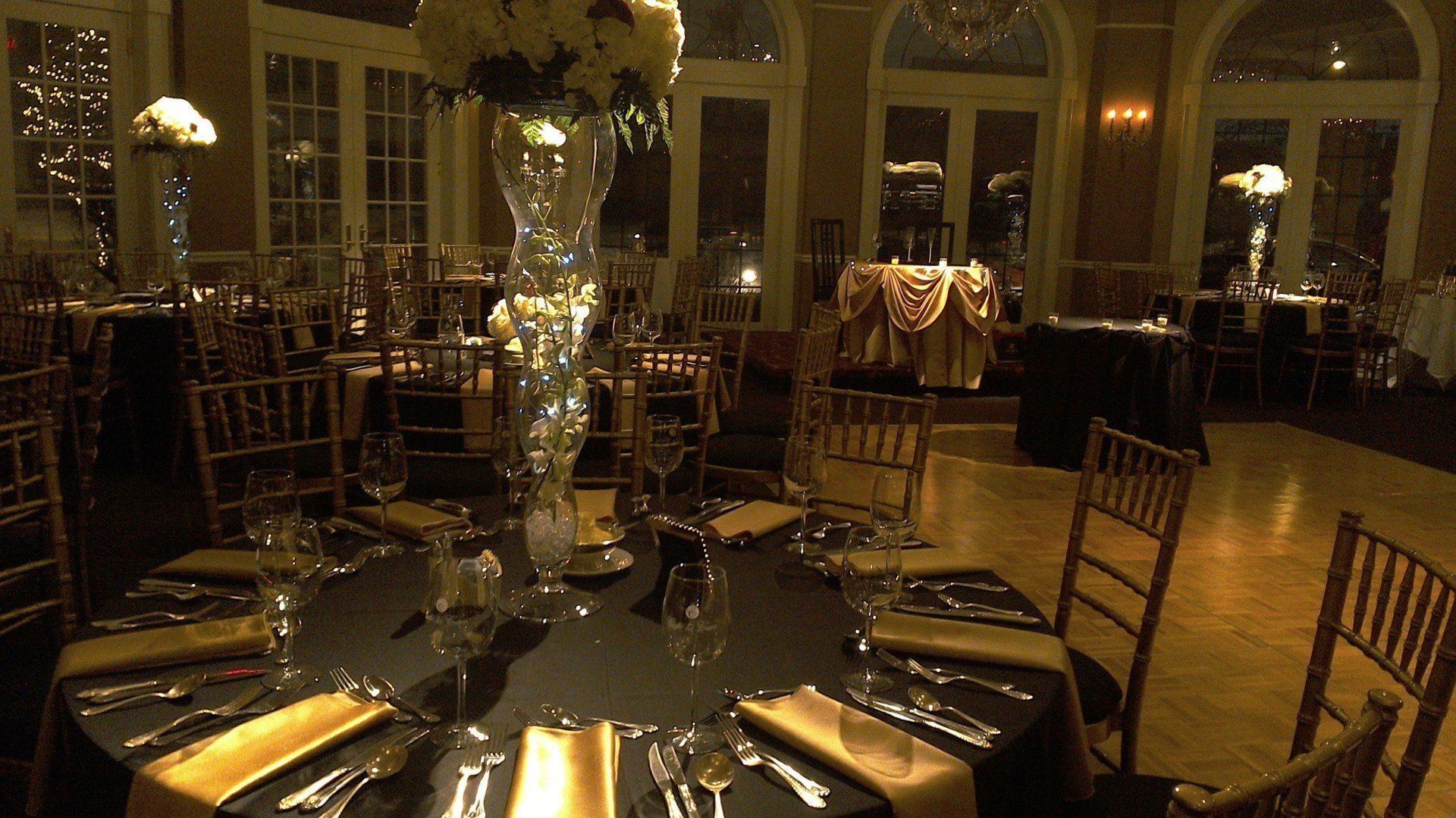 A dining room with tables and chairs set up for a wedding reception.