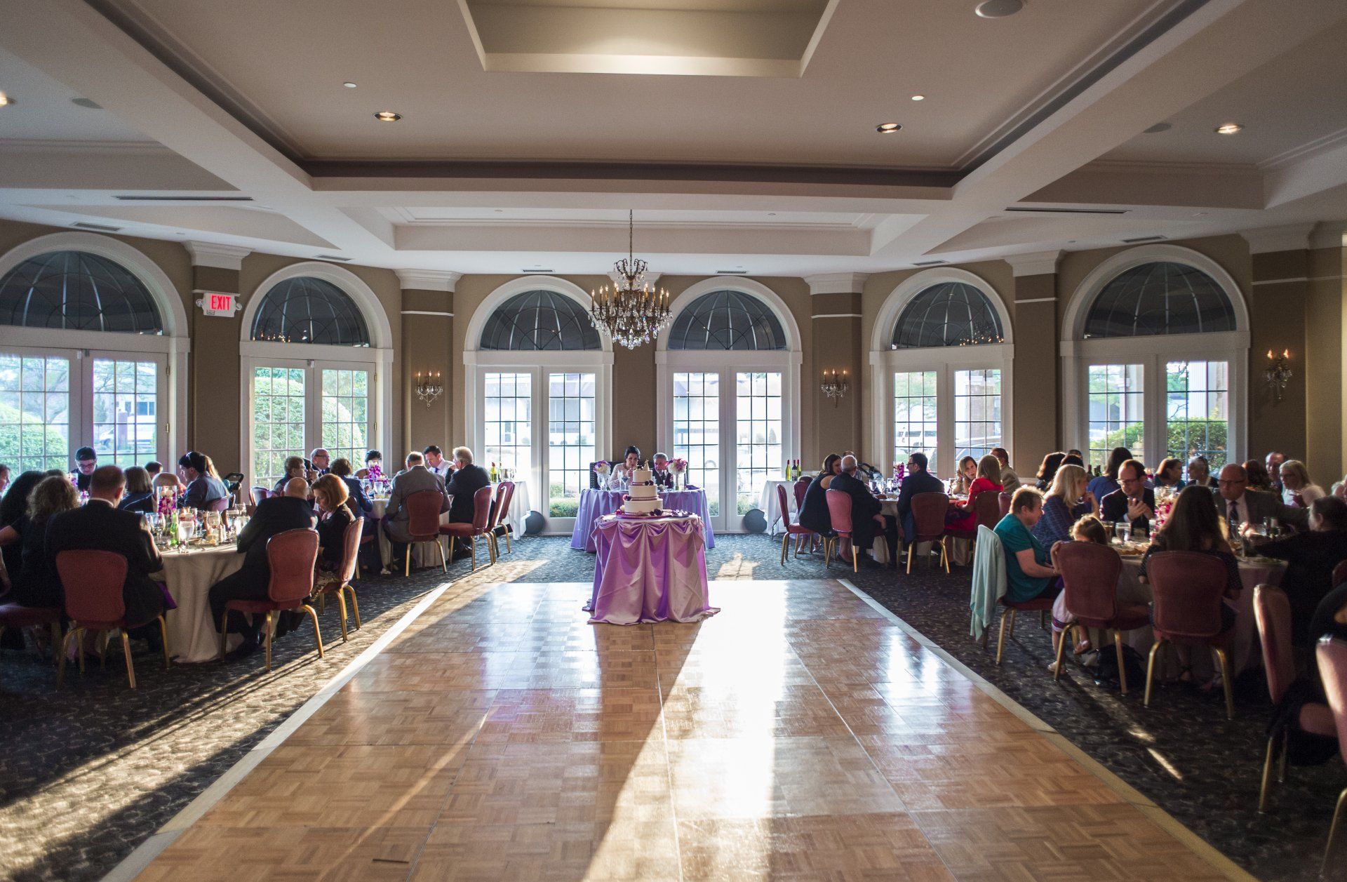 A large room filled with people sitting at tables and a dance floor.