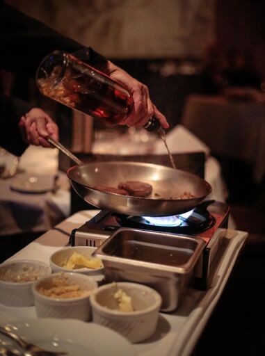 A person is pouring liquid into a frying pan