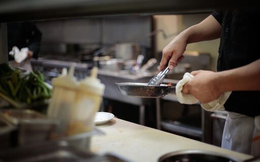 A person is cleaning a pan with a towel in a kitchen.