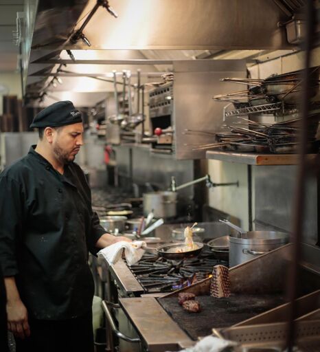 A man in a black uniform is standing in a kitchen