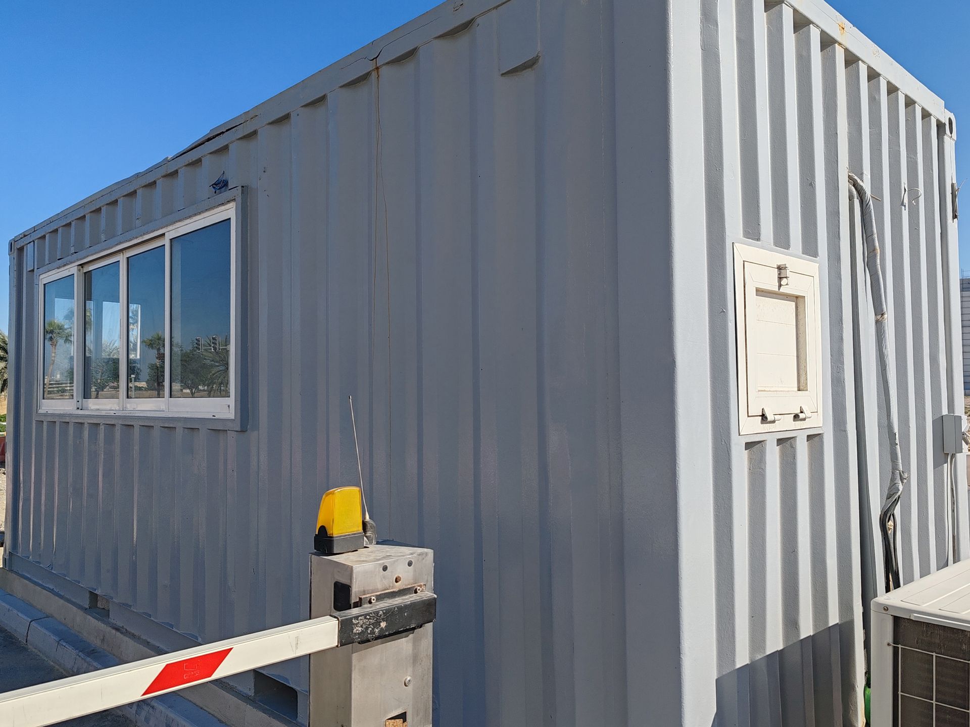 A gray building with a barrier in front of it and a window.