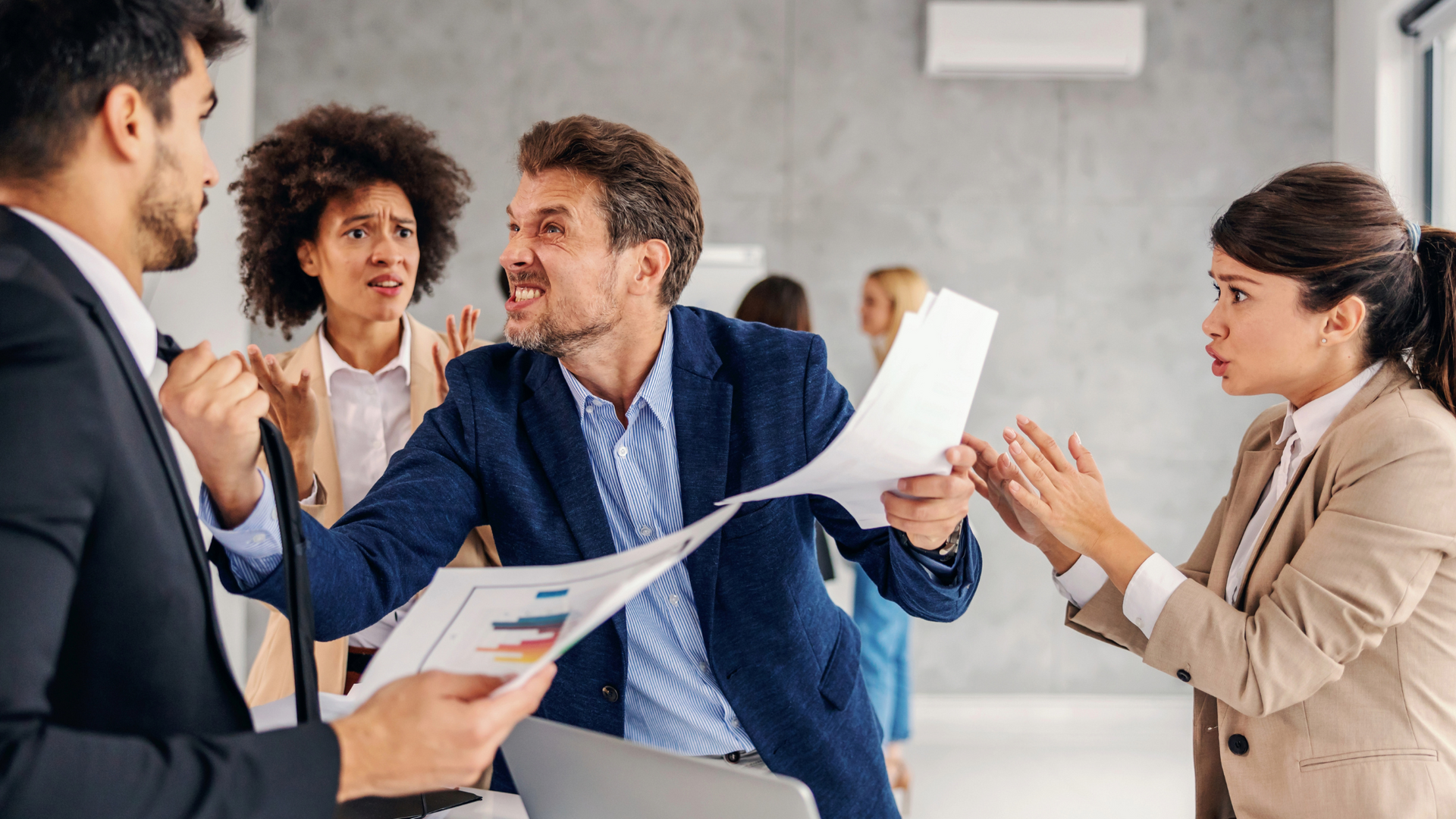 A group of business people are fighting over papers in an office.