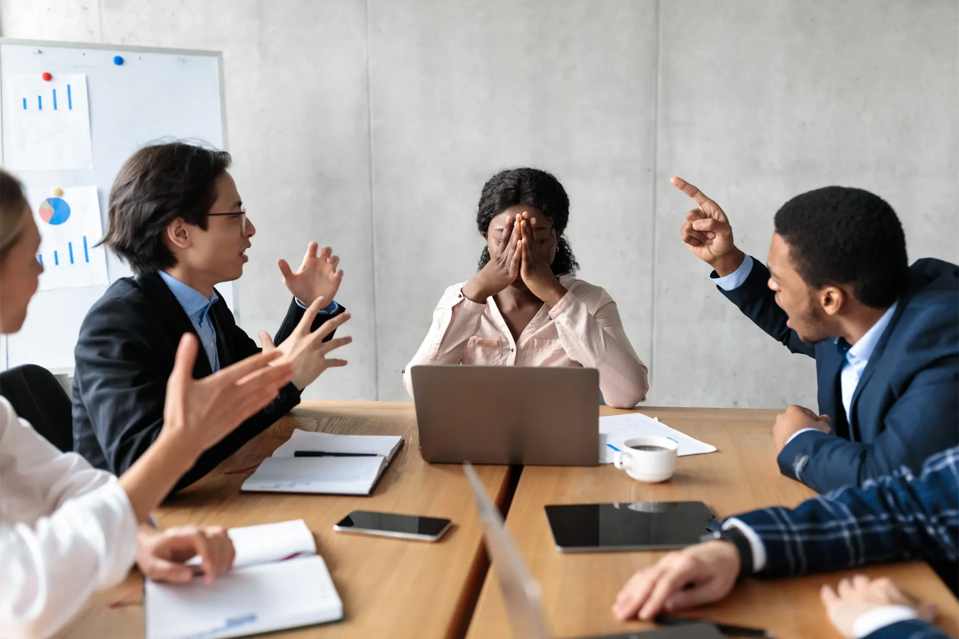 A group of people are sitting around a table with a laptop.
