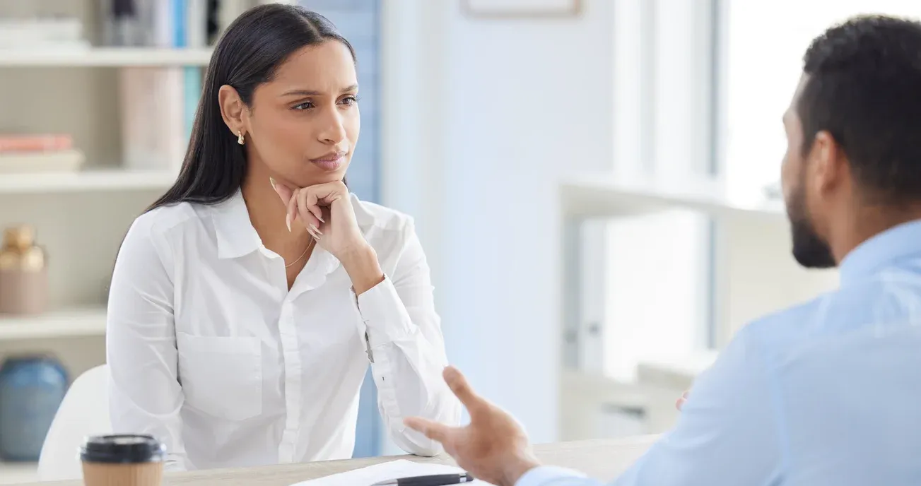 Employee and employer sit across from each other in a serious meeting.