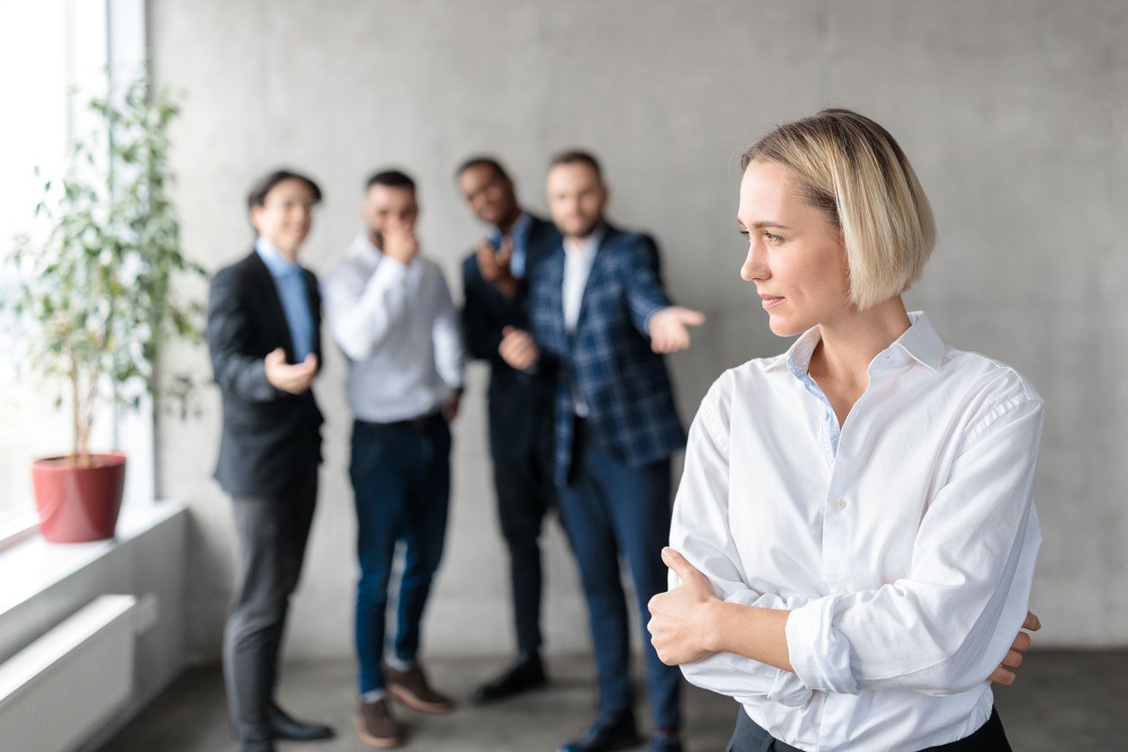 Angry looking man points at another man with his head in his hands at an office desk. 