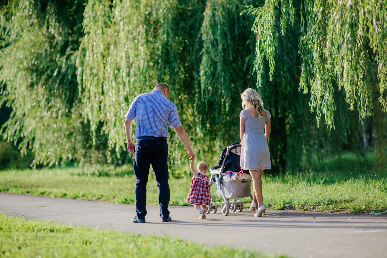 A family is walking through a field holding hands.