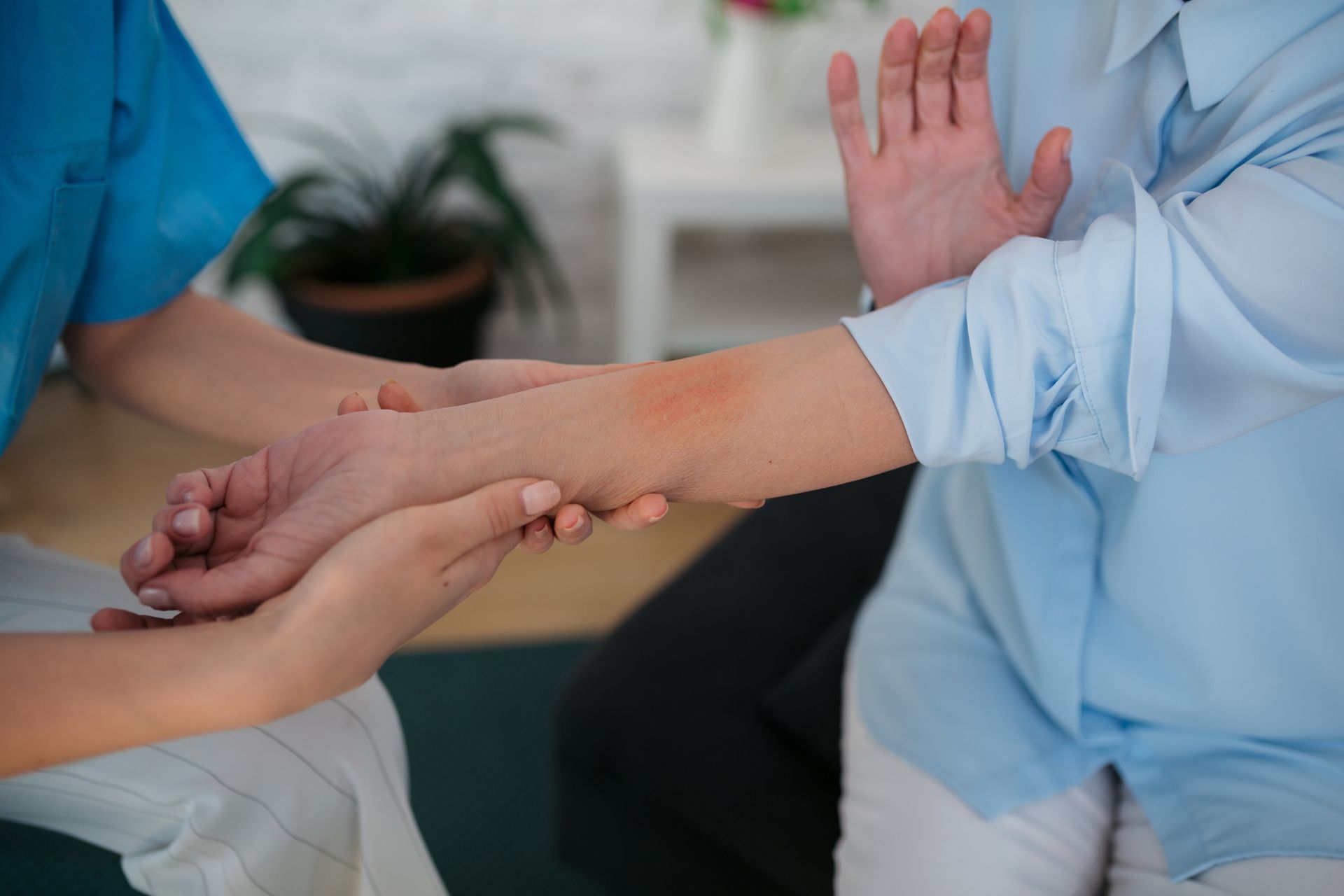 A nurse is holding the hand of an elderly woman with a rash on her arm.
