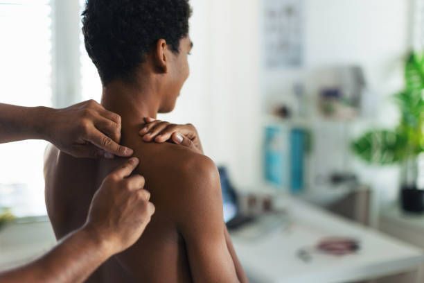 Close-up of a skin cancer doctor examining a teenage boy's skin, checking acne and moles