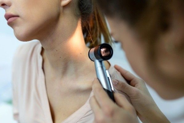 A doctor examines a woman's neck during a medical consultation in a clinical setting.