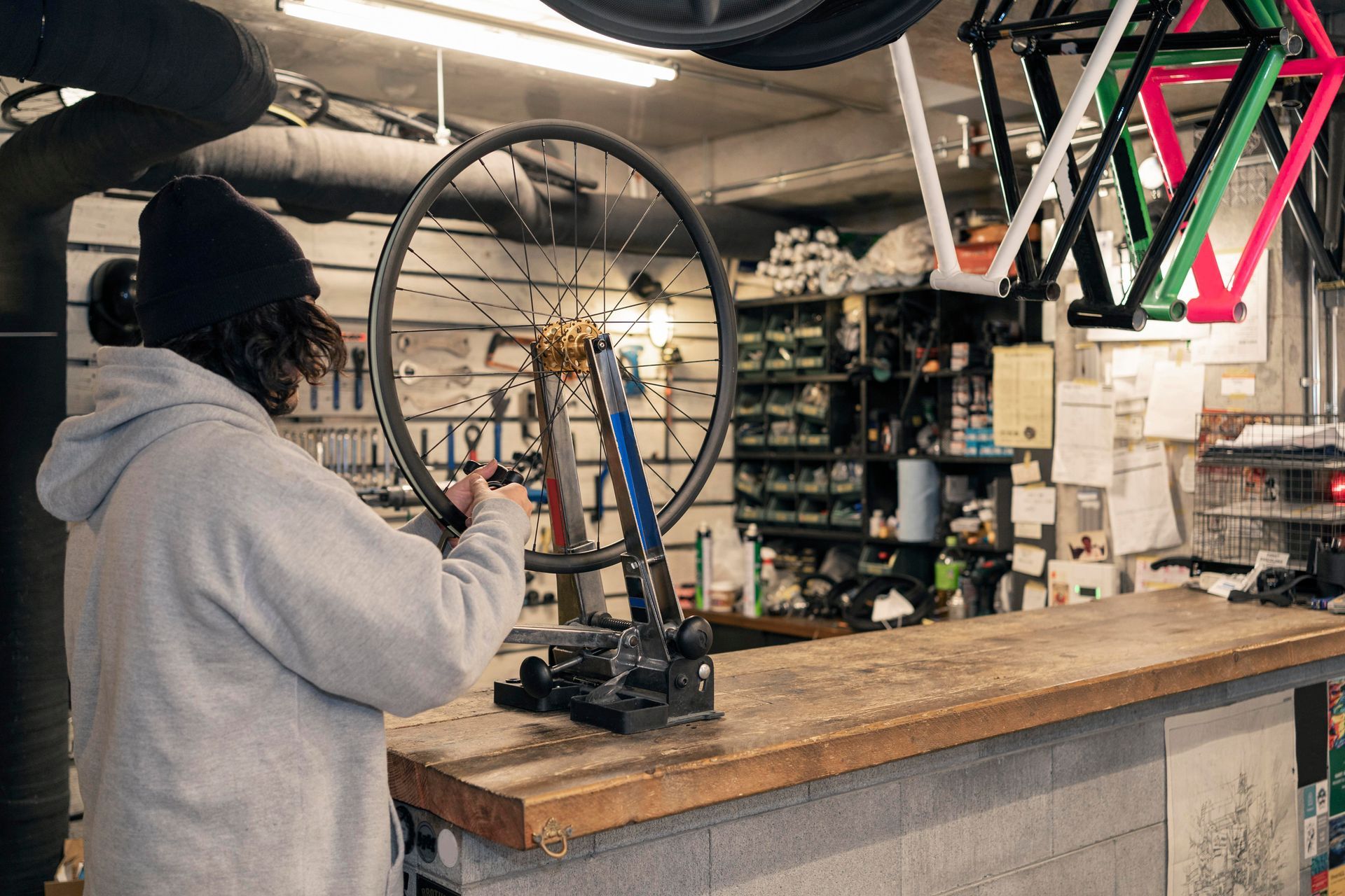 A man is working on a bicycle wheel in a garage.