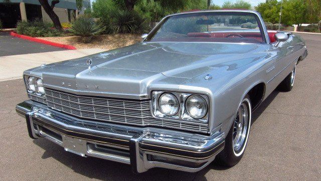 A silver car with a red top is parked on the side of the road.