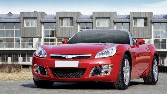 A red sports car is parked in front of a building