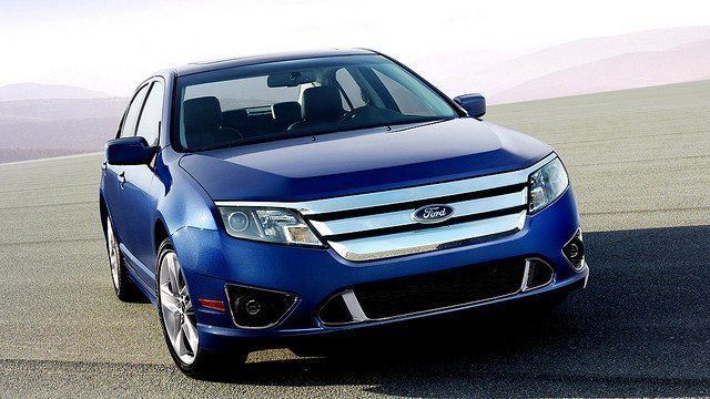 A blue ford car is parked on the side of the road