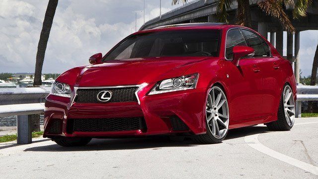 A red lexus is parked on the side of the road
