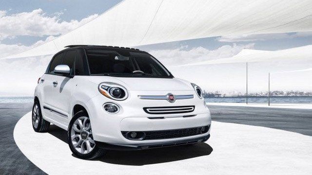 A white car is driving down a road next to a body of water.