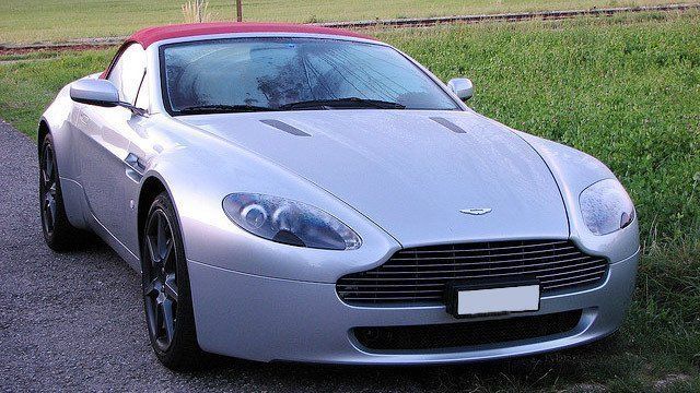 A silver sports car with a red top is parked on the side of the road.