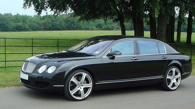 A black bentley is parked on the side of the road