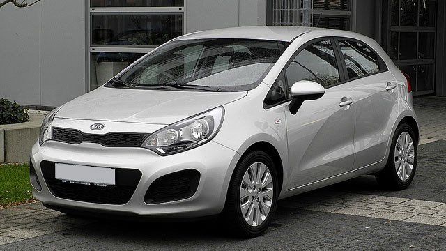 A white car is parked in front of a building.