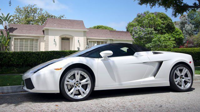 A white sports car is parked in front of a house