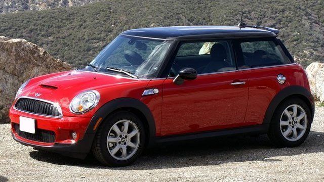 A red mini cooper is parked on a dirt road