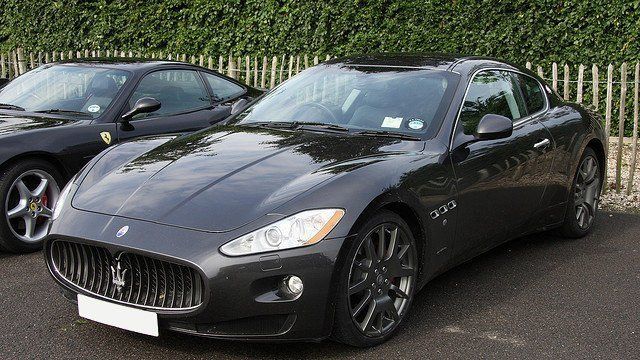 Two black sports cars are parked next to each other in a parking lot.