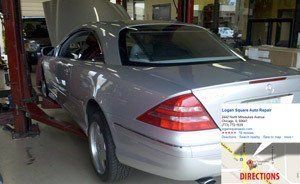A silver car is sitting on a lift in a garage.