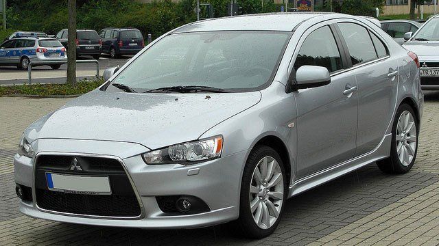 A silver mitsubishi car is parked in a parking lot