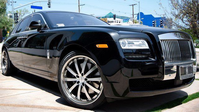 A black rolls royce is parked on the side of the road.