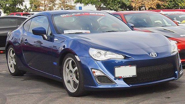 A blue sports car is parked next to a red sports car in a parking lot.