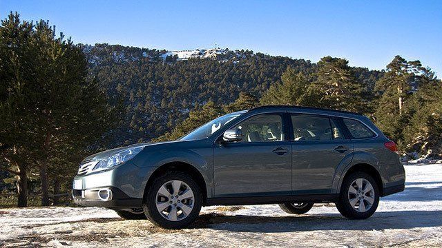 A car is parked in the snow in front of a mountain.