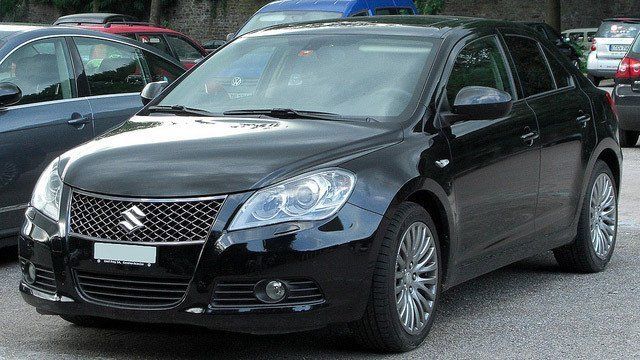 A black suzuki car is parked in a parking lot