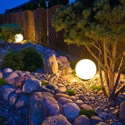 A garden with rocks and trees is lit up at night