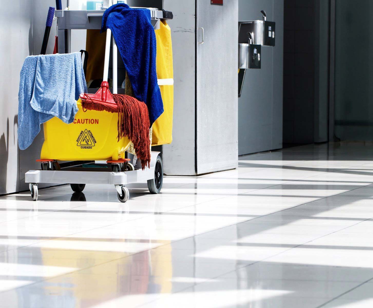 A yellow cleaning cart with a caution sign on it