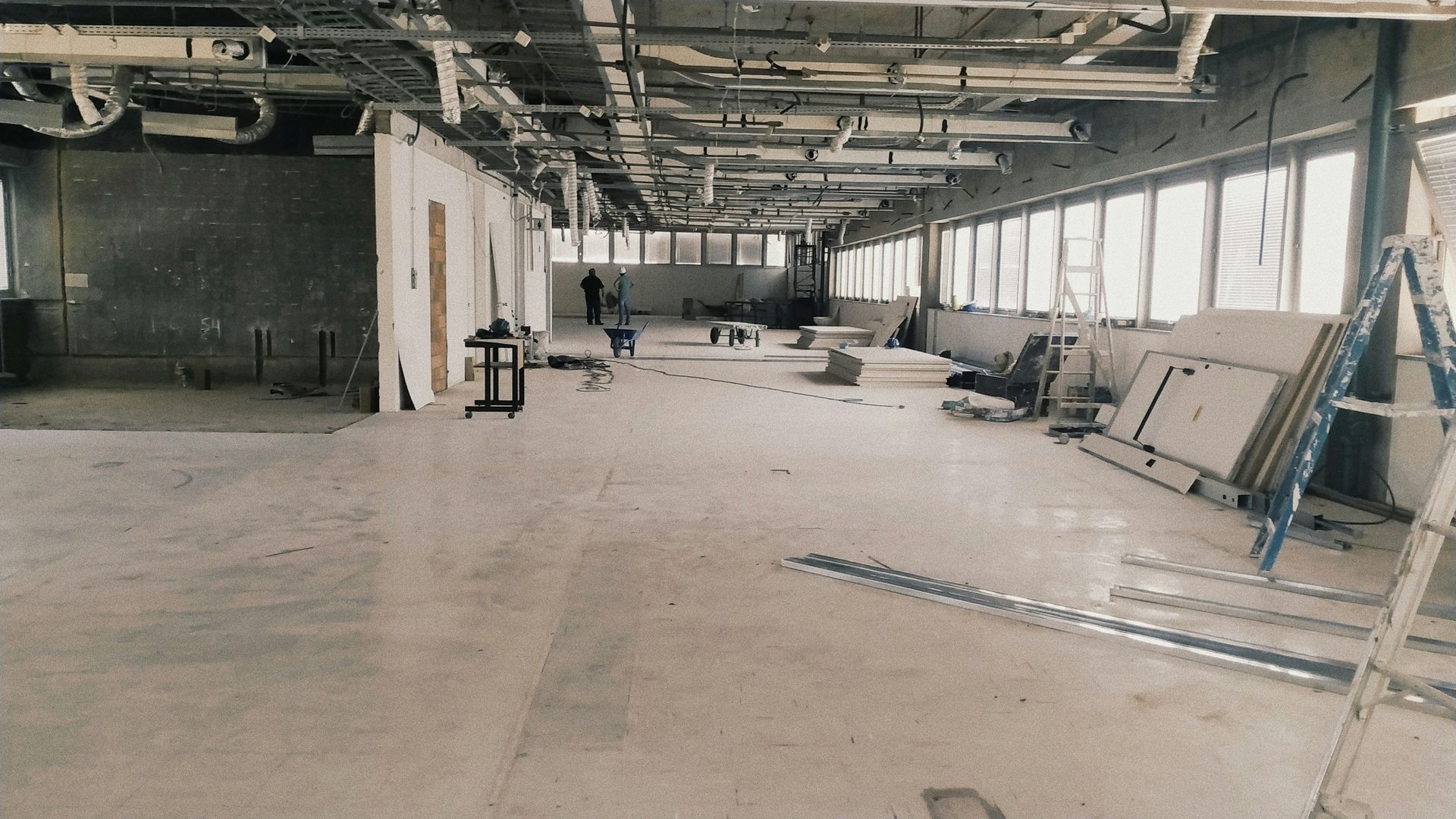 A large empty room with a lot of windows and pipes