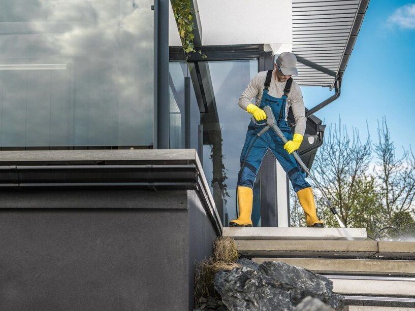 A man is cleaning the steps of a building with a broom.