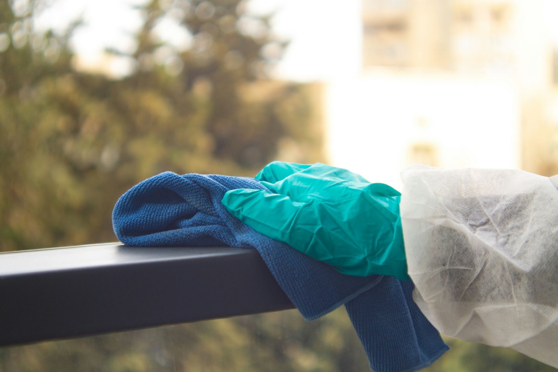 A person is cleaning a balcony with a towel and gloves.