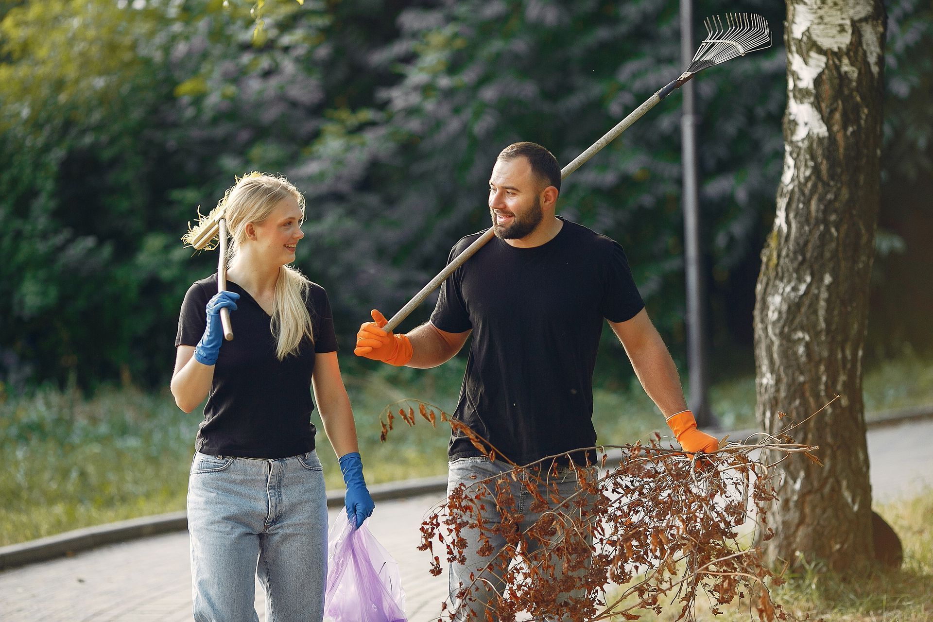 A man and a woman are picking up trash in a park.