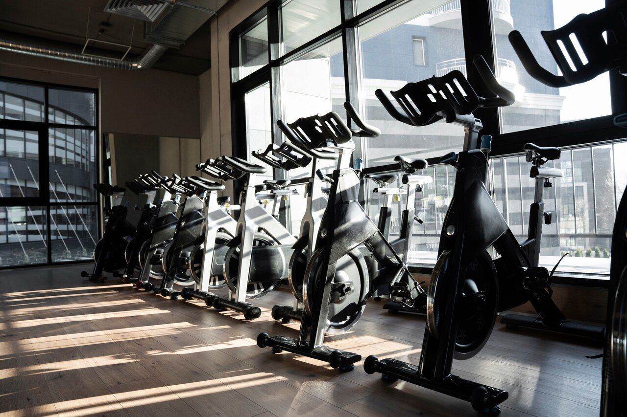 A row of exercise bikes are lined up in a gym.