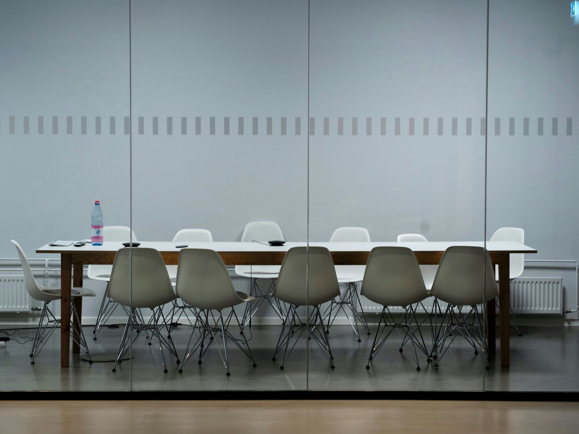 A conference room with a long table and chairs in front of a glass wall.