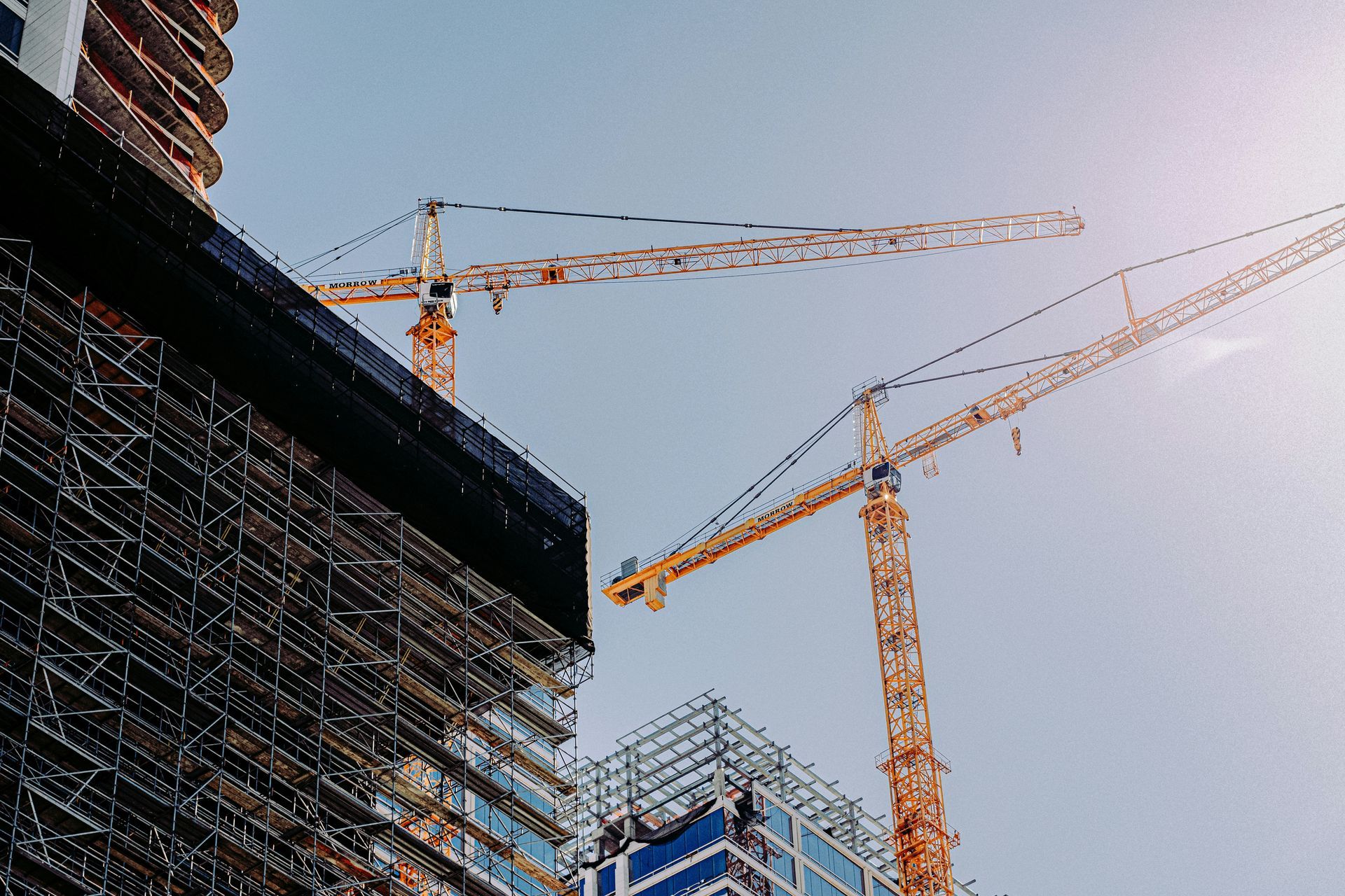 A group of construction cranes are sitting on top of a building under construction.