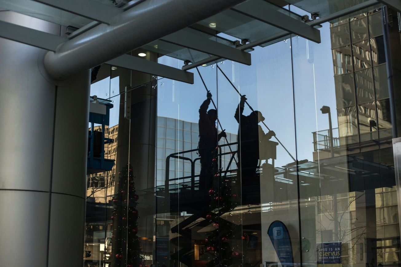 Two men are cleaning the windows of a building.