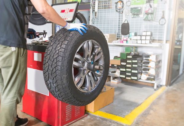 Mechanic balancing a tire on a machine in a repair shop. | Dave's Automotive LLC