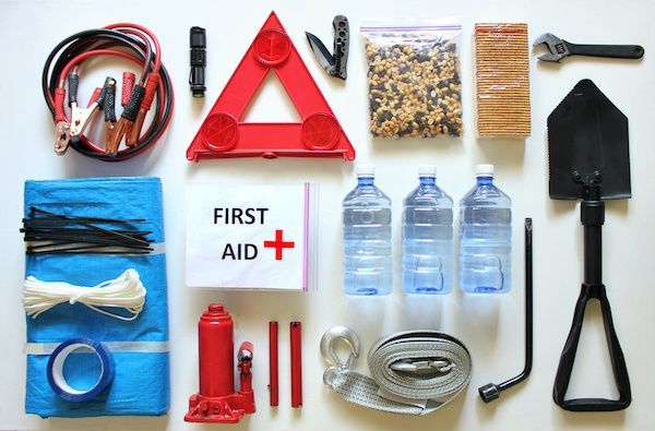Emergency car kit laid out: jumper cables, first aid, water, shovel, tools, warning triangle, etc. | Dave's Automotive LLC