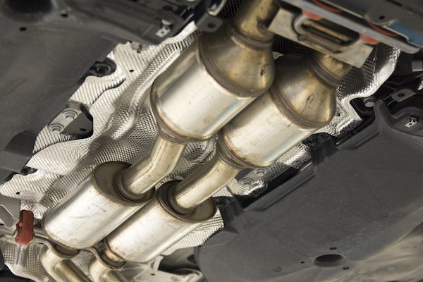 Underside of a car showing two catalytic converters with silver exhaust pipes and heat shields. | Dave's Automotive LLC
