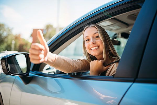 Smiling woman in car giving thumbs up. | Dave's Automotive LLC