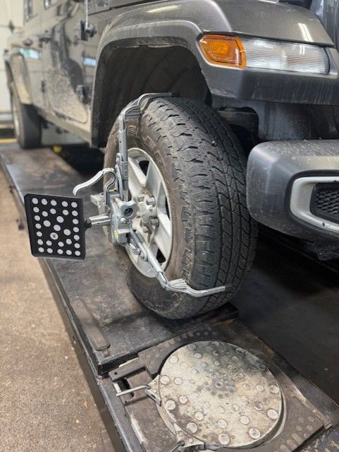 Jeep tire with alignment equipment attached, on a vehicle lift. | Dave's Automotive LLC